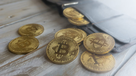 Golden Bitcoins with leather wallet on a wooden tableの写真素材