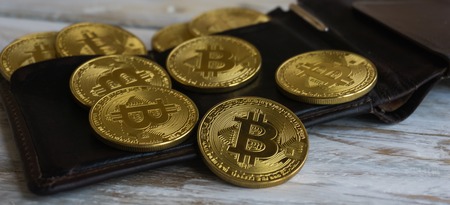 Golden Bitcoins with leather wallet on a wooden tableの写真素材