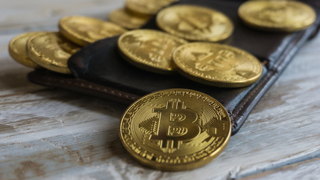 Golden Bitcoins with leather wallet on a wooden tableの写真素材