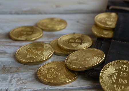 Golden Bitcoins with leather wallet on a wooden tableの写真素材