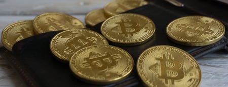 Golden Bitcoins with leather wallet on a wooden tableの写真素材