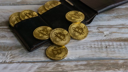Golden Bitcoins with leather wallet on a wooden tableの写真素材