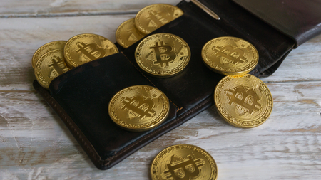 Golden Bitcoins with leather wallet on a wooden tableの写真素材