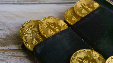 Golden Bitcoins with leather wallet on a wooden tableの写真素材