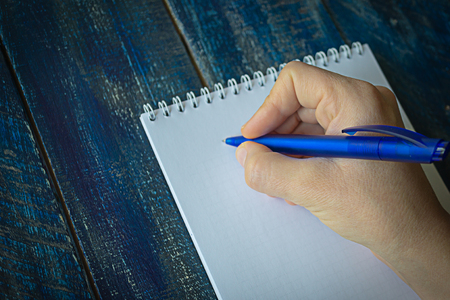 Closeup image of hand writing down on a blank. Top view of female hands making some notes work, studying, shopping, blogging conceptの写真素材