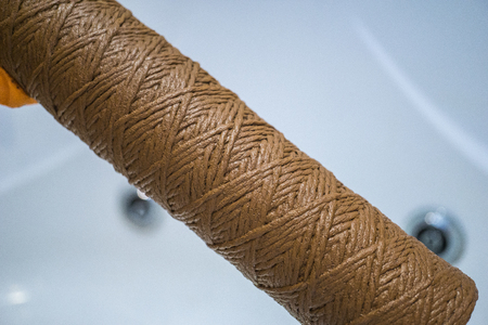 Hand holding dirty water filter cartridge over the bathhub.の写真素材