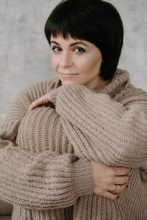 Gorgeous young brunette woman in warm knitted sweater posing on the bedの写真素材