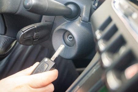 Closeup inside vehicle of hand holding key in ignition, start engine key