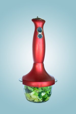 kitchen hand blender with a bowl filled with fruits and vegetables for making vitamin smoothiesの写真素材