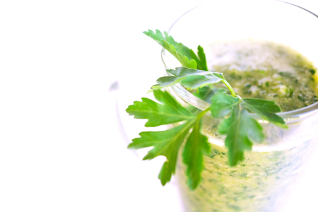 Green fruit and vegetable smoothie with a sprig of parsley in a transparent glass mug on a white background. healthy diet. food high in vitamins.の写真素材