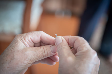 an elderly woman sews torn clothes. close-up of women's hands with thread and needle. the concept of...