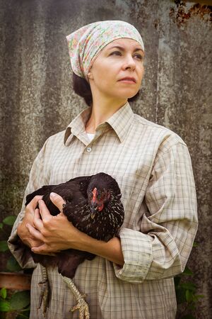 Organic farmer holding chicken under his armsの写真素材