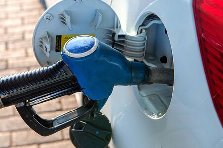 A gun for filling gasoline is inserted into the gas tank of the car. Holding fuel nozzle to refuel gasoline for carの写真素材