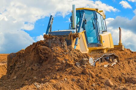 Crawler bulldozer - excavator with clipping path on a background with blue sky and clouds. work on construction site or sand pit.の写真素材