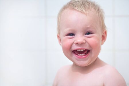 Happy funny little boy smiling in the bathroom. happy funny baby laughing and bathed in the bathの写真素材