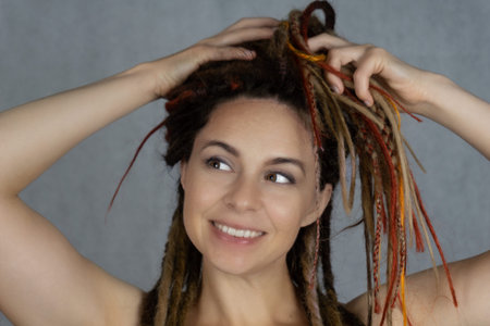 studio prtrait of young stylish beautiful smiling caucasian girl with dreadlocks hairstyle. Fashion...