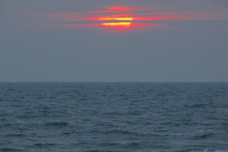 beautiful red sunset over the ocean. Bright sunset with large yellow sun under the sea surface. sundown seascape.の写真素材