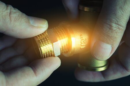 Plumber hands screwing nut of pipe over plumbing tools background. Concept of repair and technical assistance. Close up shot. Brutal atristic toning.の写真素材