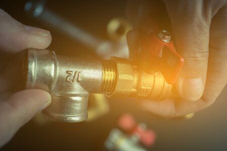 Plumber hands screwing nut of pipe over plumbing tools background. Concept of repair and technical assistance. Close up shot. Brutal atristic toning.の写真素材