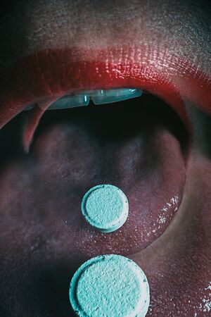 Double exposure. Woman taking pill. tablet in the mouth of the woman, close-up face. atistic toning. arifical noise.の写真素材