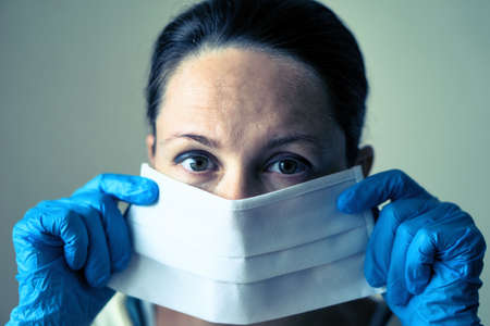 portrait of female doctor wearing protective mask and looking at camera posing against white background.の写真素材