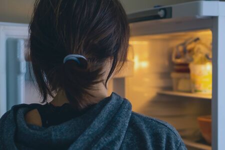 Rear View Of A Woman Looking In Open Refrigerator At Home or Kitchen.の写真素材