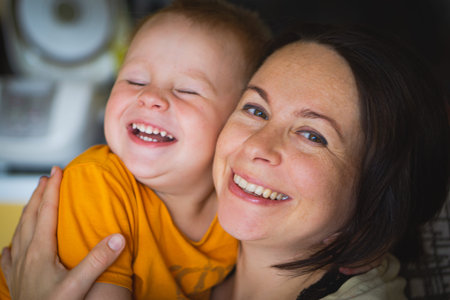 Happy family laughing faces, mother holding adorable child baby boy, smiling and hugging, close up...