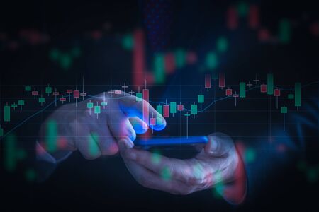 Businessman checking stock market data using a mobile phone. Analysis economy and market data analytics concept.の写真素材