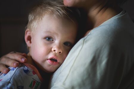 A tearful little boy clings to his mother to calm down. A mothers care and custody. The relationship between parents and childrenの写真素材