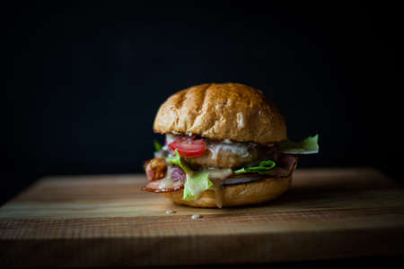fresh tasty burger on black background. Delicious fresh homemade burger on a wooden tableの写真素材