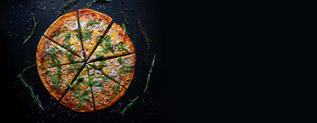 Tasty fresh baked pizza with tomatoes and basil on black background. Top view of hot delicious pizza. With copy space for text. Flat lay. Bannerの写真素材