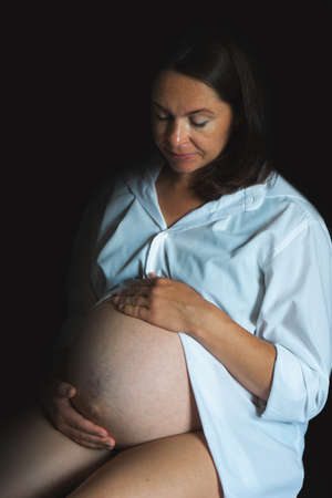 Pregnant woman sitting on bed in sunlight. Pregnancy and motherhood conceptの写真素材