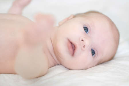 new born girl age two weeks is lying in bed and looking around with interestの写真素材