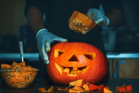 man cutting a jack-o-lantern pumpkin to halloween celebration.の写真素材