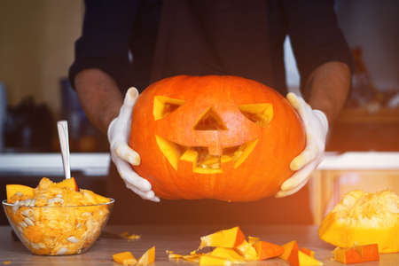 man cutting a jack-o-lantern pumpkin to halloween celebration.の写真素材