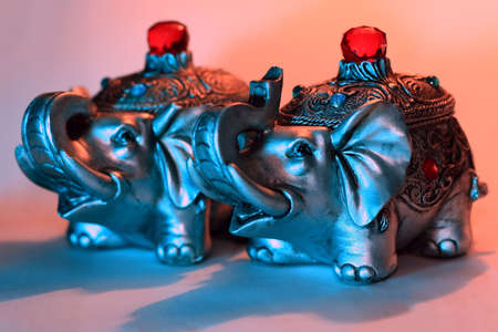 Two silvery elephants-caskets looking aside placed on a white surfaceの写真素材