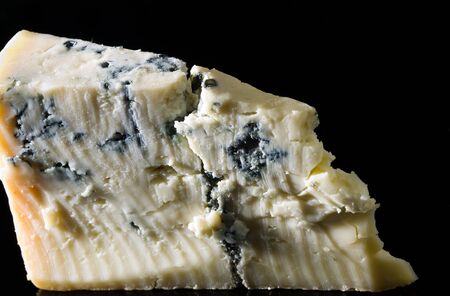 Piece gorgonzola cheese isolated on black with reflectionの写真素材