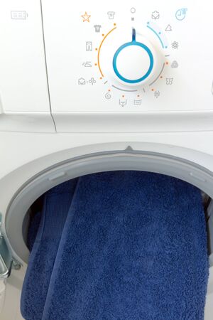 Open washing machine with control panel dial and blue  towelの写真素材