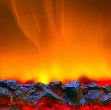Electric fireplace with a burning coals and red-orange backgroundの写真素材