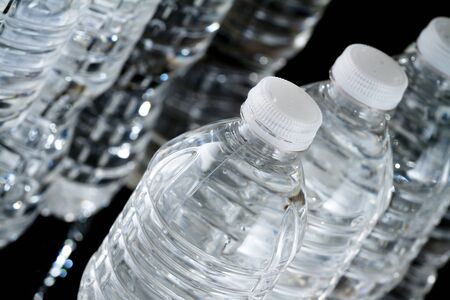 A row of plastic bottles of water on black backgroundの写真素材
