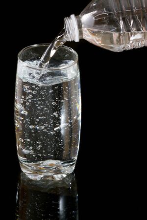 Pouring fresh cold water into the glass from plastic bottle の写真素材