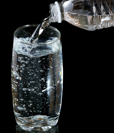 Pouring fresh cold water into the glass from plastic bottle の写真素材
