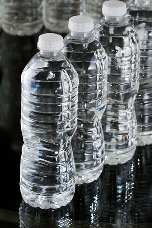 A row of plastic bottles of water on black backgroundの写真素材