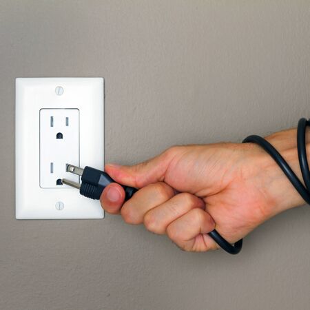 Electric cable on the hand and Electrical Outlet on the Wall  Power 110v の写真素材