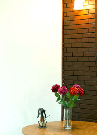 Vase with  flowers on the table and brick wall backgoundの写真素材