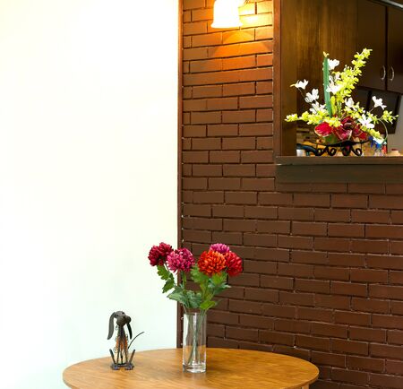 Vase with  flowers on the table and brick wall backgoundの写真素材