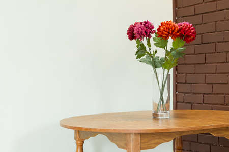 Vase with  flowers on the table and brick wall backgoundの写真素材