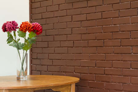 Vase with  flowers on the table and brick wall backgoundの写真素材