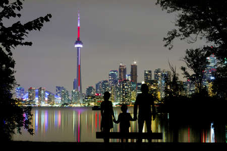 Silhouettes of family watching Toronto Downtown Skyline at nightのeditorial素材
