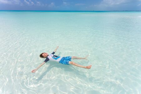 Kid floating on a back in the beautiful seaの写真素材